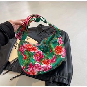 Detailed close-up of green silk hobo bag with traditional peony and phoenix floral patterns