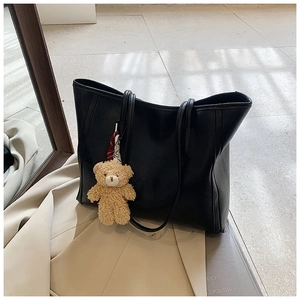 Detail of black large-capacity tote bag in textured PU leather with a cute bear charm