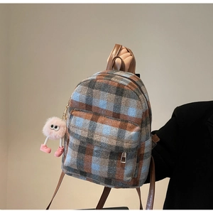 Detailed close-up of a mini plaid backpack with a cute pink plush pompom charm accessory