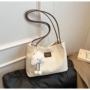 Dettaglio borsa tote in velluto a coste bianco crema con etichetta in pelle e ciondolo nuvola