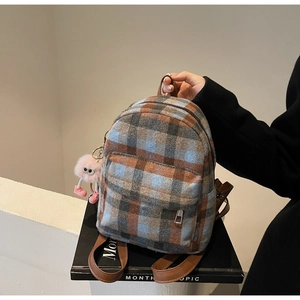 Detail of British style plaid tweed backpack with brown PU leather straps and plush charm