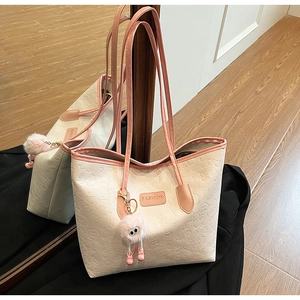Detail of cream tote bag with pink embossed cartoon graffiti and plush charm