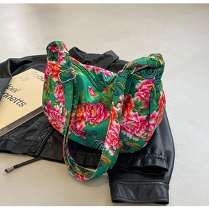 Detail of floral and phoenix print shoulder bag on black leather jacket with book