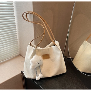 Dettaglio borsa tote bianca intrecciata con spalline in pelle marrone e ciondolo a nuvola