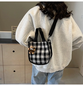 Close-up of black and white checkered crossbody bag with cute plush pendant and strap