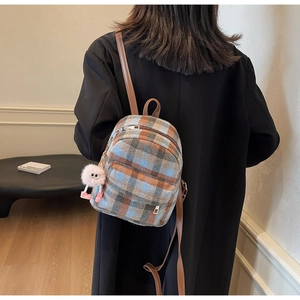 Close-up of a plaid mini backpack featuring orange and blue tweed with a pink plush charm