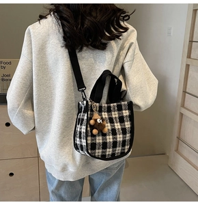 Model wearing a black and white checkerboard tweed mini tote bag with a small bear charm