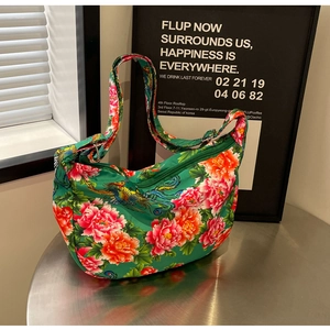 Detail view of large green floral tote bag with phoenix pattern on a metal table