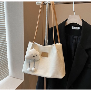 Dettaglio della borsa tote intrecciata bianca con patch in pelle e ciondolo nuvola