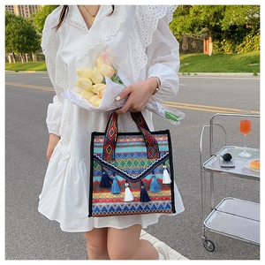 Close-up of ethnic woven tote bag with colorful geometric patterns and fringe tassels