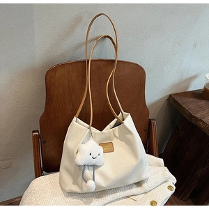 Dettaglio borsa tote in velluto a coste crema con manici marroni e ciondolo a nuvola