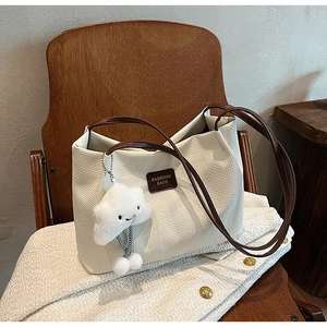 Dettaglio borsa tote in velluto bianco con cinturini in pelle e ciondolo a nuvola