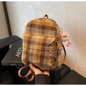 Detailed close-up of brown plaid wool mini backpack with leather straps and plush charm