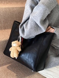 Large black matte leather tote bag with a cute brown plush bear charm for daily commute