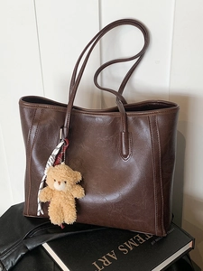 Large dark brown tote bag with retro leather texture and plush bear charm on white background