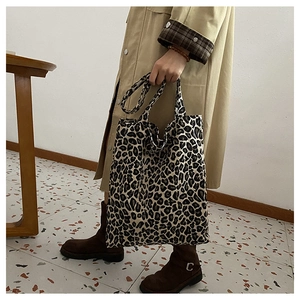 Side view of large leopard print tote bag being held by a model in a minimalist room