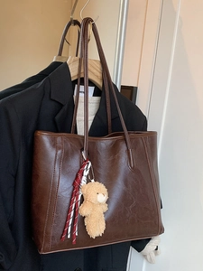 Deep brown faux leather tote bag with plush bear charm and slender double straps