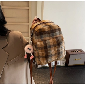 Detail of mini plaid backpack featuring pink plush charm and metal zipper closures