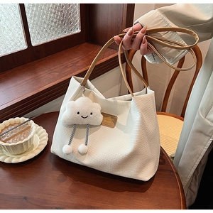 Dettaglio della borsa tote in velluto a coste bianco crema con manico in pelle e charm