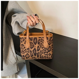 Dettaglio della borsa a secchiello leopardata con hardware dorato e manici in pelle marrone