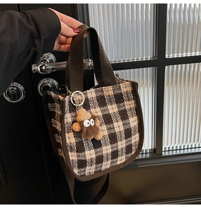 Detailed view of brown checkered woven handbag with a cute plush monster charm accessory
