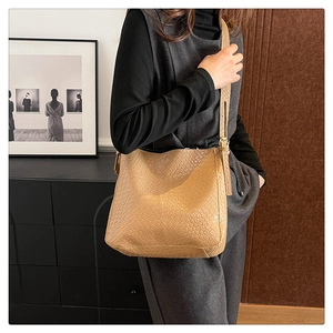 Detailed side view of khaki woven leather shoulder bag with adjustable strap for women