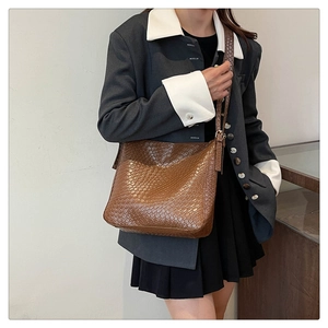 Brown woven PU leather crossbody bag worn by a model in a minimalist style setting