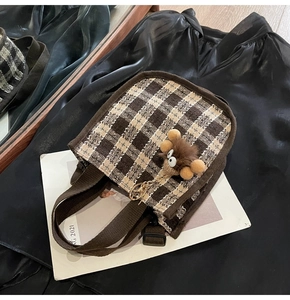 Detail view of brown checkerboard canvas handbag with cute plush animal charm accessory