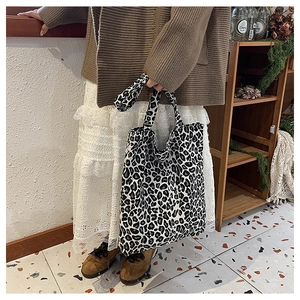 Detail of a large leopard print tote bag styled with a cozy cardigan and lace skirt
