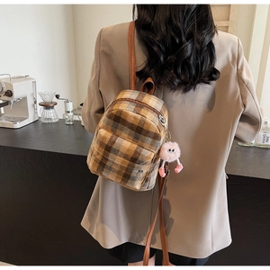 Plaid canvas mini backpack featuring brown leather straps and a pink plush charm detail