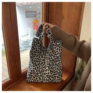 Detail of leopard print canvas tote bag held against a cozy wooden window background