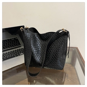 Detail of black woven texture and gold buckles on a large capacity shoulder tote bag