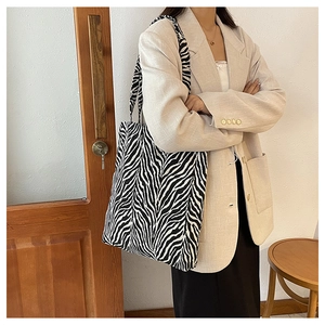 Detailed view of a zebra print canvas tote bag styled with a professional beige blazer