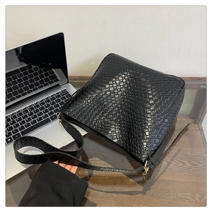 Detail of black woven texture and gold metal buckle on a stylish shoulder bag