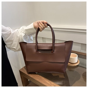 Detailed close-up of dark coffee leather tote bag featuring matte texture and top handle