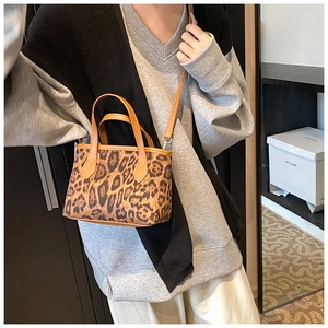 Dettaglio di una mini borsa tote leopardata vintage con tracolla su una modella