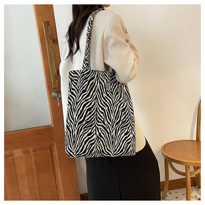 Detail of large zebra print tote bag shown on model with minimalist indoor background