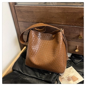 Detailed texture of brown woven leather hobo bag with tassel accent on dark background