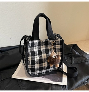 Close-up of black and white checkered tweed handbag with a plush monster charm