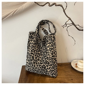 Detailed view of leopard print tote bag placed on a textured wooden surface