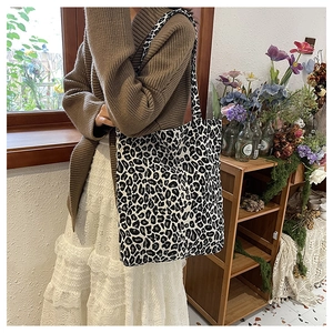 Detail view of large leopard print canvas tote bag on model in a cozy home setting
