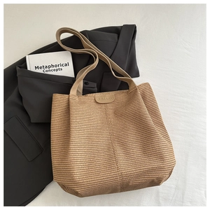 Close-up of woven straw tote bag featuring a leather brand tag and wide shoulder strap
