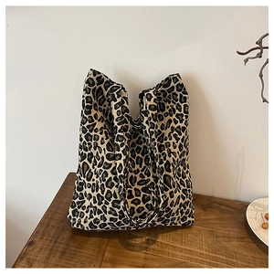 Close-up of leopard print canvas tote bag on a wooden surface with a soft white background