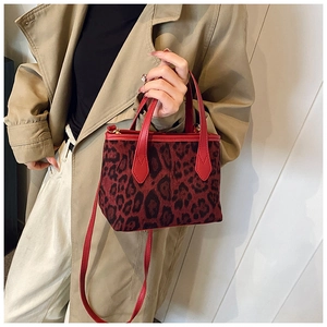 Borsa a secchiello leopardata con cinturini in pelle rossa abbinata a un trench coat