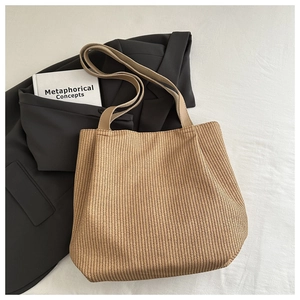 Detail of woven straw tote bag texture styled with a blazer and book for daily commute