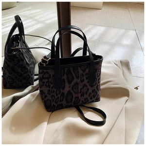Dettaglio borsa a secchiello leopardata con manico in pelle nera e finiture metalliche dorate