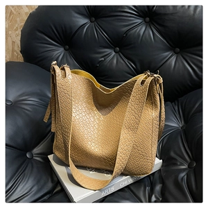 Detailed macro view of khaki hobo bag featuring woven texture on a minimalist shoulder strap