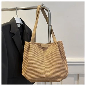 Detail of hand-woven straw tote bag with JUMAITU leather patch and long shoulder straps