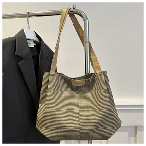 Close-up of woven tote bag texture with leather logo plate and shoulder straps