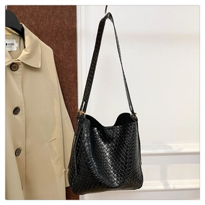 Close-up of black woven leather texture on a spacious shoulder bag with intricate details